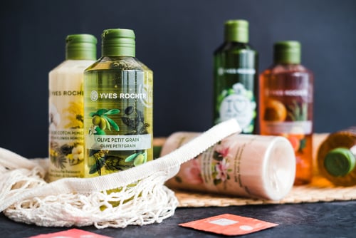 verschiedene Pflegeprodukte der Marke Yves Rocher vor einer schlichten dunklen Wand sind zu sehen.