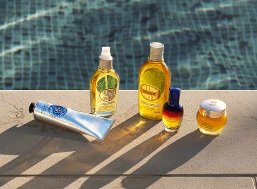 Verschiedene Produkte der Marke L‘Occitane stehen auf einer Poolkante.